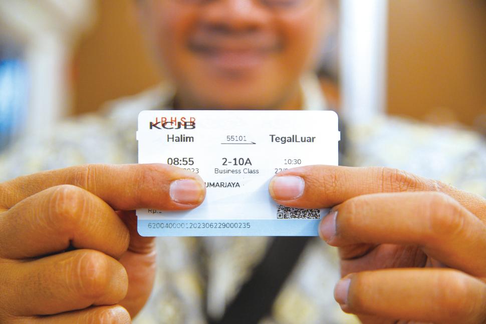 6月22日，在印度尼西亚雅万高铁正在进行联调联试的综合检测列车上，一名记者展示纪念样票（图源：新华社）